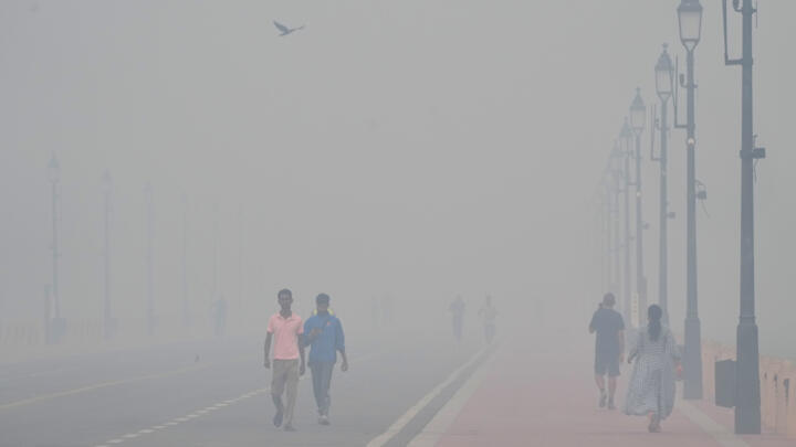 People walk in the morning near the India Gate monument amidst morning smog a day after Diwali festival in New Delhi, India, Tuesday, Oct. 21, 2025.
