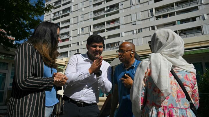 Amine Kessaci (C) speaks with residents after voting in the second round of legislative elections at a polling station in Marseille, southern France, on July 7, 2024.