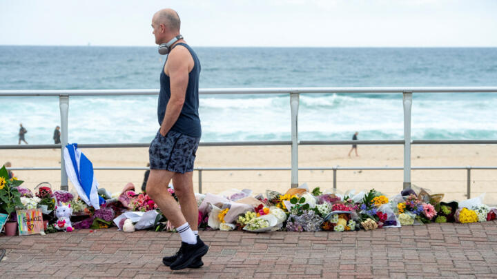 A man walks along the promenade at Bondi Beach, while looking at a floral tribute to honour the victims of a mass shooting targeting a Hanukkah celebration on Sunday at Bondi Beach, in Sydney