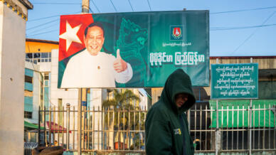 A man walks past a campaign billboard for Sunday polls in Myanmar the military is touting as a return to democracy and international observers are decrying as a sham