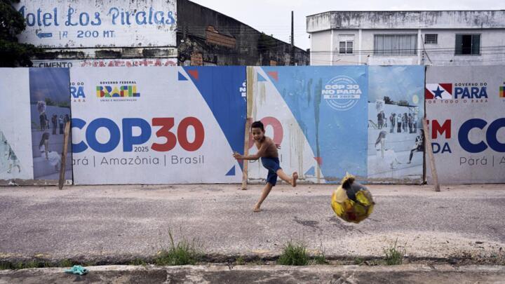 A boy kicks a football near a COP30 sign in Belem, Brazil, on March 23, 2025.