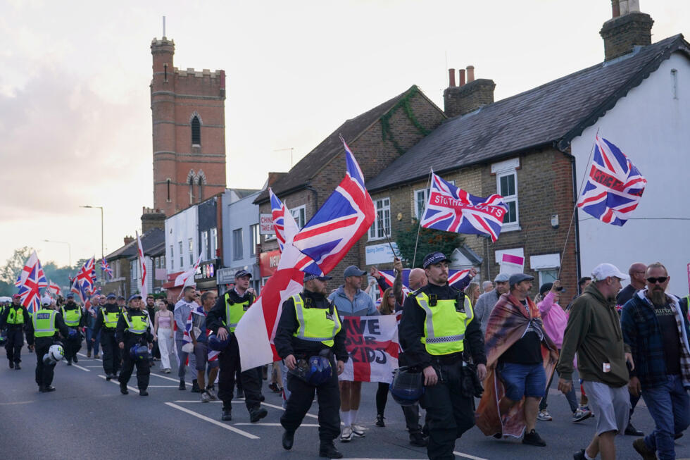 Police officers escort protesters near Epping, London after a temporary block on housing asylum seekers at a local hotel was overturned.