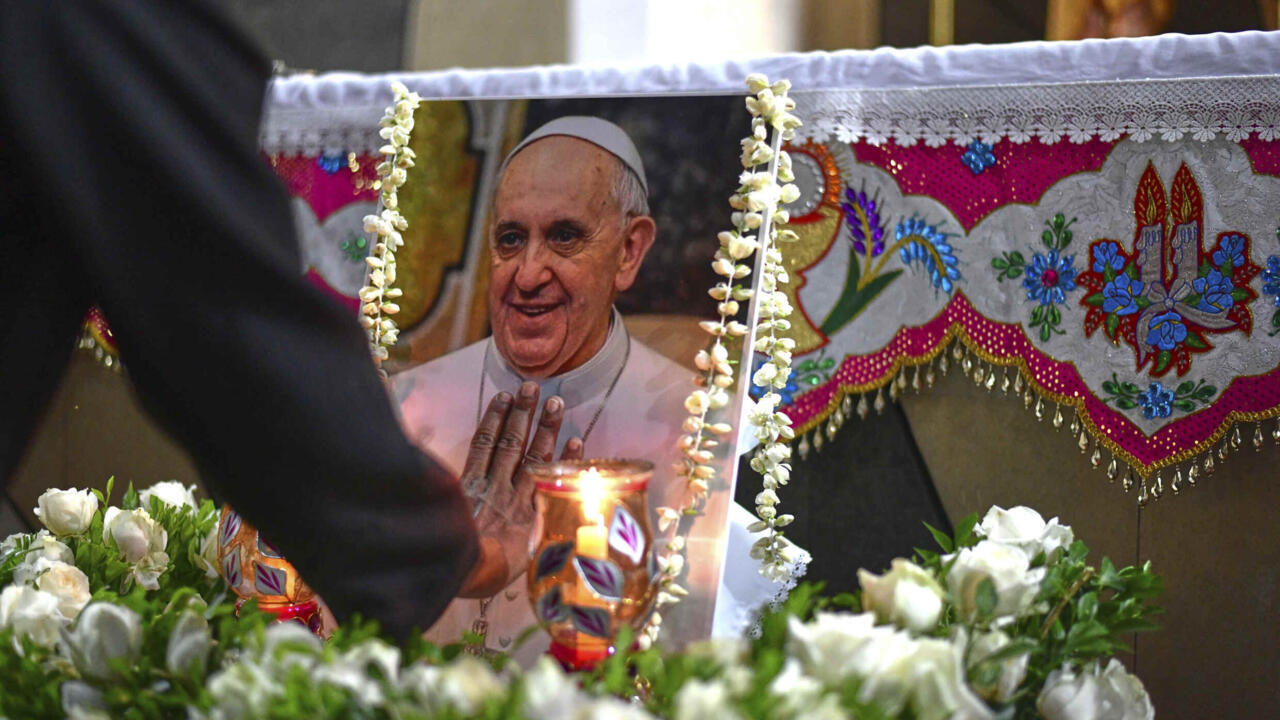 A Catholic nun touches a portrait of Pope Francis following the announcement of his death by the Vatican on April 21, 2025.